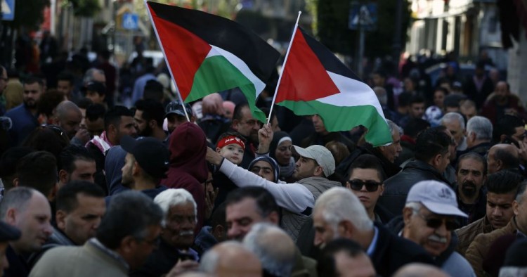 Palestinians wave national flags as they march in the streets of the occupied West Bank city of Ramallah, calling for the cessation of divisions between Fatah and Hamas and the unification of the West Bank and Gaza Strip, on January 12, 2019. 