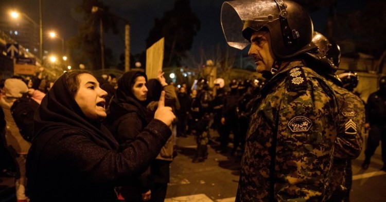 A woman attending a candlelight vigil, in memory of the victims of Ukraine International Airlines Boeing 737, talks to a policeman following the gathering in front of the Amirkabir University in the Iranian capital Tehran on January 11, 2020. 