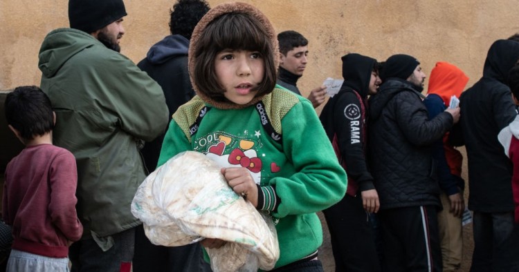  A displaced Syrian girl carries a bag of bread in a stadium which has been turned into a makeshift refugee shelter on February 19, 2020 in Idlib, Syria.