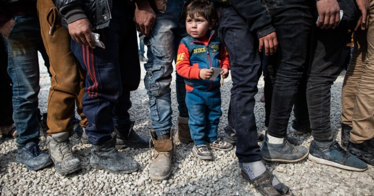 Displaced Syrians wait in a queue as an NGO delivers bread as they wait to receive humanitarian aid in a stadium which has been turned into a makeshift refugee shelter on February 19, 2020 in Idlib, Syria.