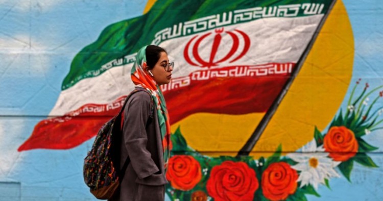 A woman walks past a mural with the Iranian national flag in Tehran, on February 20, 2020 on the eve of parliamentary election. 