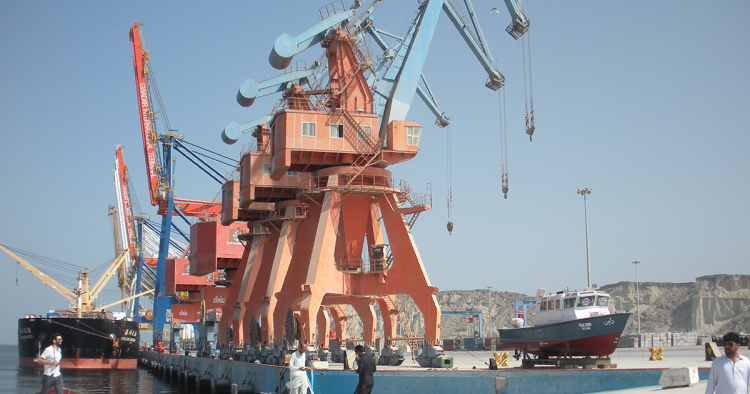 In this photograph taken on October 4, 2017, Pakistani labourers walk through Gwadar port. Remote and impoverished, Pakistan's Gwadar port at first glance seems an unlikely crown jewel in a multi-billion dollar development project with China aimed at constructing a 21st century Silk Road. Situated on a barren peninsula in the Arabian Sea, Gwadar, or the "gate of the wind", owes its fortuitous selection as Pakistan's next economic hub to its strategic location near the Strait of Hormuz. 