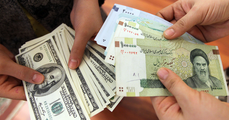 This picture illustrates Iranians on January 12, 2012 counting and exchanging the United States 100-dollar bills and Iran's Rial banknotes, bearing a portrait of Iran's late founder of Islamic Republic Ayatollah Ruhollah Khomeini in Tehran. The Rial's plunge, to 18,000 to the dollar hit a record low on January 18, based on rates in black market trading that the government has tried to ban.