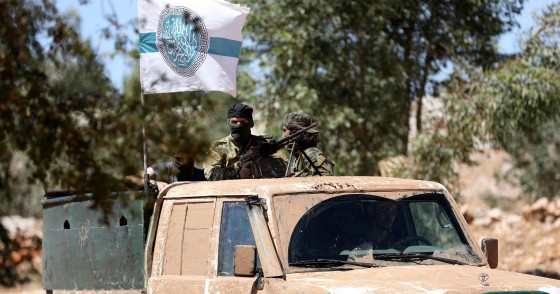 Syrian fighters stand at the back of a pick-up as they attend a mock battle in anticipation of an attack by the regime on Idlib province and the surrounding countryside, during a graduation of new Hayat Tahrir al-Sham (HTS) members at a camp in the countryside of the northern Idlib province.