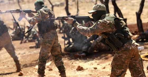 Syrian fighters fire AK-47 at a mock battle during a graduation of new Hayat Tahrir al-Sham (HTS) members