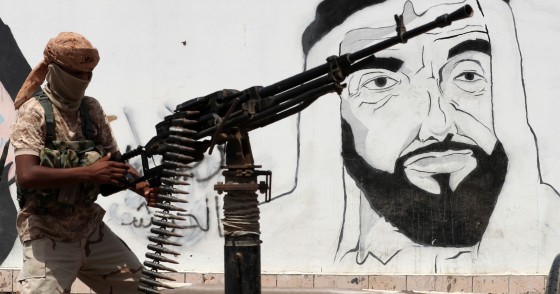 A picture taken on August 8, 2018 during a trip in Yemen organised by the UAE's National Media Council (NMC) shows a soldier loyal to the Saudi and UAE-backed government, manning a machine gun mounted on a vehicle passing by a mural depicting the late UAE founder and president Sheikh Zayed bin Sultan al-Nahyan, along a street in the southeastern port city of Mukalla, the capital of Hadramawt province. 