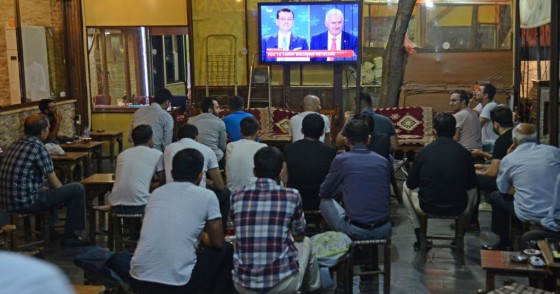 People watch a live broadcast of a televised debate between Istanbul's mayoral candidate Binali Yildirim (R) of Turkey's ruling AKP, and Istanbul's deposed mayor Ekrem Imamoglu (L) of the CHP, is shown on a screen at a tea house in Diyarbakir on June 16, 2019.