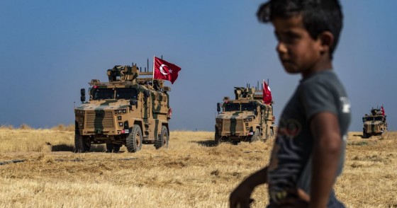 A Syrian boy watches as Turkish military vehicles, part of a US military convoy, take part in joint patrol in the Syrian village of al-Hashisha on the outskirts of Tal Abyad town along the border with Turkey, on October 4, 2019.