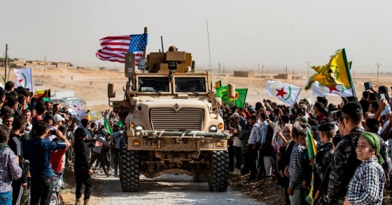 Syrian Kurds gather around a US armoured vehicle during a demonstration against Turkish threats next to a US-led international coalition base on the outskirts of Ras al-Ain town in Syria's Hasakeh province near the Turkish border on October 6, 2019.