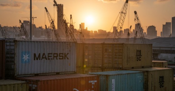 The sun sets behind the urban skyline as port cranes and shipping containers sit in an industrial transport area in Beirut, Lebanon, on 11 October 2019.