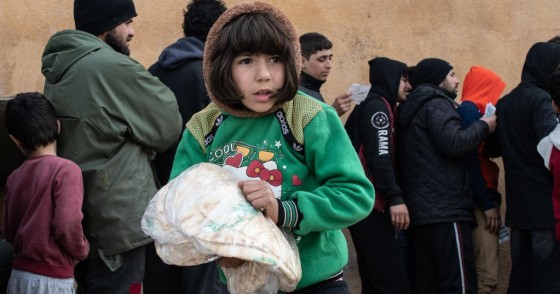  A displaced Syrian girl carries a bag of bread in a stadium which has been turned into a makeshift refugee shelter on February 19, 2020 in Idlib, Syria.