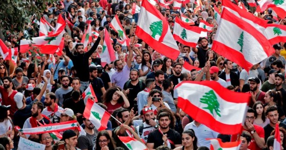 Lebanese protesters wave national flags during demonstrations to demand better living conditions and the ouster of a cast of politicians who have monopolised power and influence for decades, on October 21, 2019 in downtown Beirut. -