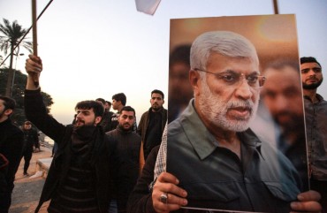 Supporters of the predominantly Shia Muslim Popular Mobilization Forces (PMF) gather with flags and posters of the PMF deputy head Abu Mahdi al-Muhandis during an anti-US protest after the US airstrike in Baghdad