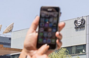 An Israeli woman uses her iPhone in front of the building housing the Israeli NSO group, on August 28, 2016, in Herzliya, near Tel Aviv.