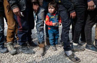 Displaced Syrians wait in a queue as an NGO delivers bread as they wait to receive humanitarian aid in a stadium which has been turned into a makeshift refugee shelter on February 19, 2020 in Idlib, Syria.