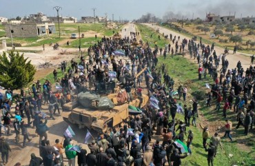 Syrians in protest climb atop a Turkish military M60T tank and infantry-fighting vehicle (IFV) as they attempt to block traffic on the M4 highway, which links the northern Syrian provinces of Aleppo and Latakia, before incoming joint Turkish and Russian military patrols (as per an earlier agreed upon ceasefire deal) in the village of al-Nayrab, about 14 kilometres southeast of the city of Idlib and seven kilometres west of Saraqib in northwestern Syria on March 15, 2020