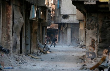 A man cleans in a street near destroyed buildings in the Palestinian camp of Yarmuk southern Damascus on November 1, 2018. - Former residents of the Palestinian camp of Yarmuk are desperately counting on help from abroad to help raise the once-bustling neighbourhood back out of the rubble.