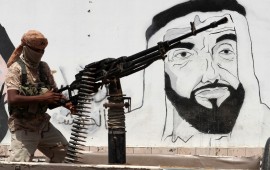A picture taken on August 8, 2018 during a trip in Yemen organised by the UAE's National Media Council (NMC) shows a soldier loyal to the Saudi and UAE-backed government, manning a machine gun mounted on a vehicle passing by a mural depicting the late UAE founder and president Sheikh Zayed bin Sultan al-Nahyan, along a street in the southeastern port city of Mukalla, the capital of Hadramawt province.
