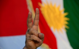  A demonstrator makes the "victory" sign standing in front of a Kurdish flag. 